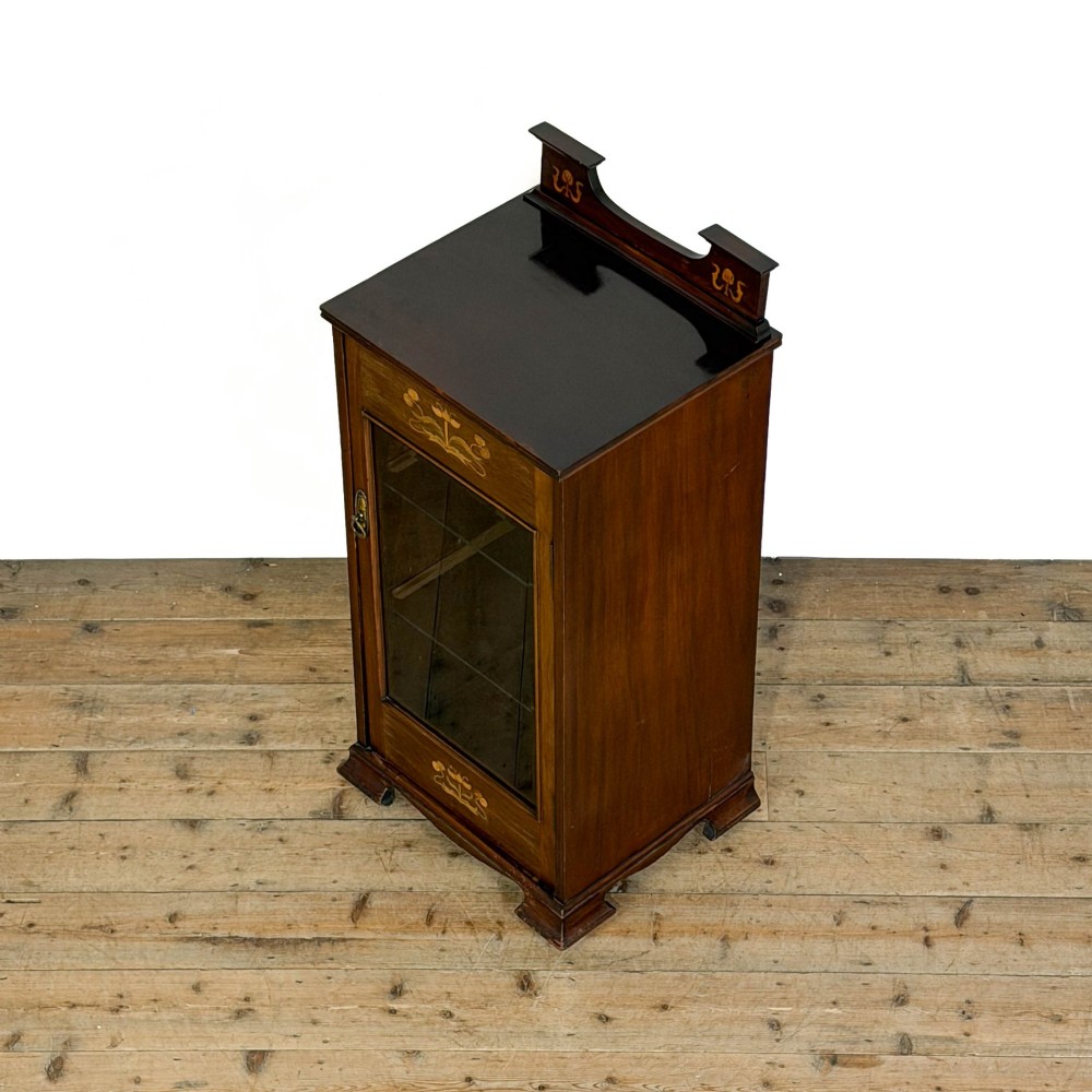 An antique dark wood Art Nouveau display cabinet featuring floral marquetry inlays, a single glazed glass door, and a shaped cresting gallery. View VII