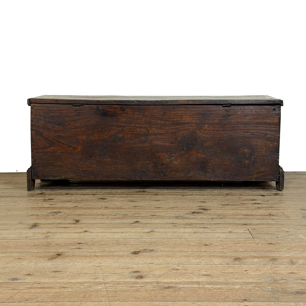 A rectangular George III dark elm blanket chest with a hinged lid, brass escutcheon, and bracket feet. View VII