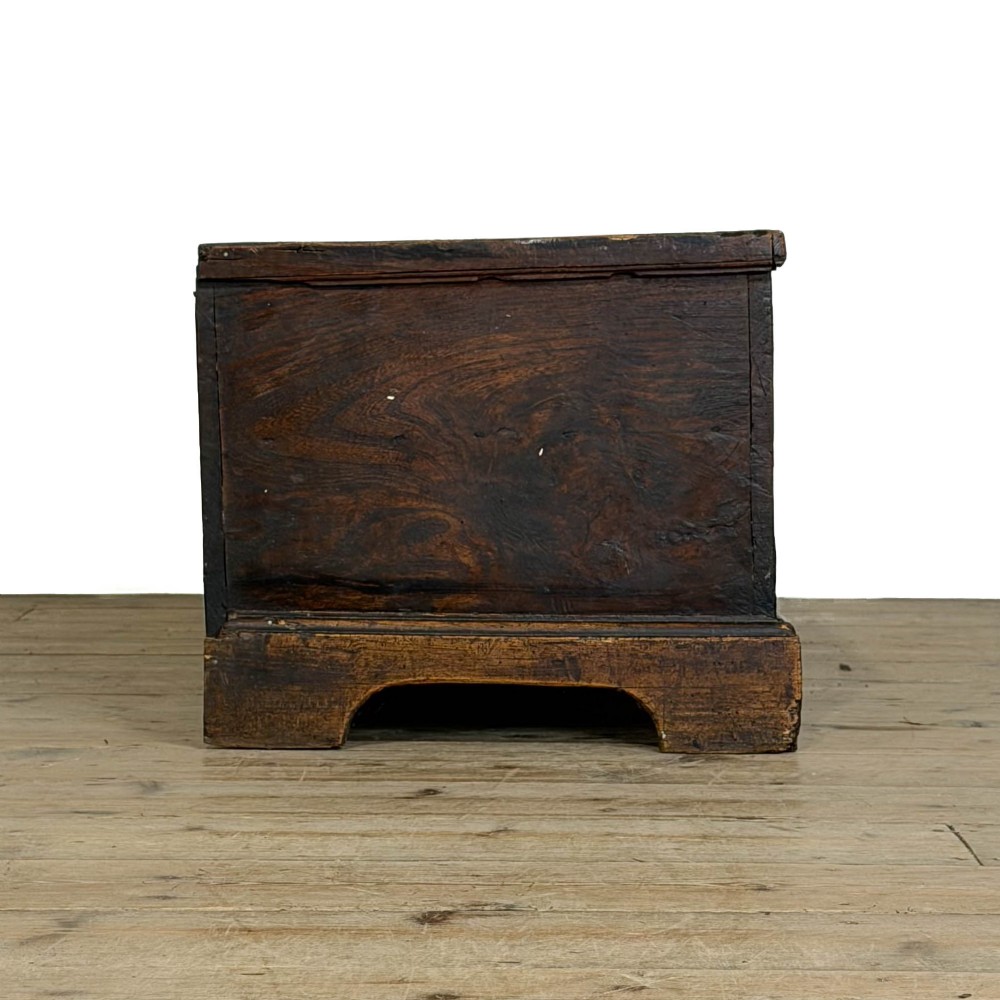 A rectangular George III dark elm blanket chest with a hinged lid, brass escutcheon, and bracket feet. View VIII