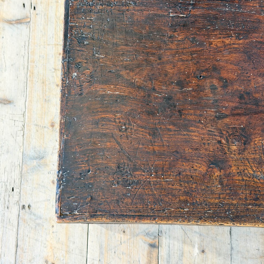 A rectangular George III dark elm blanket chest with a hinged lid, brass escutcheon, and bracket feet. View IX