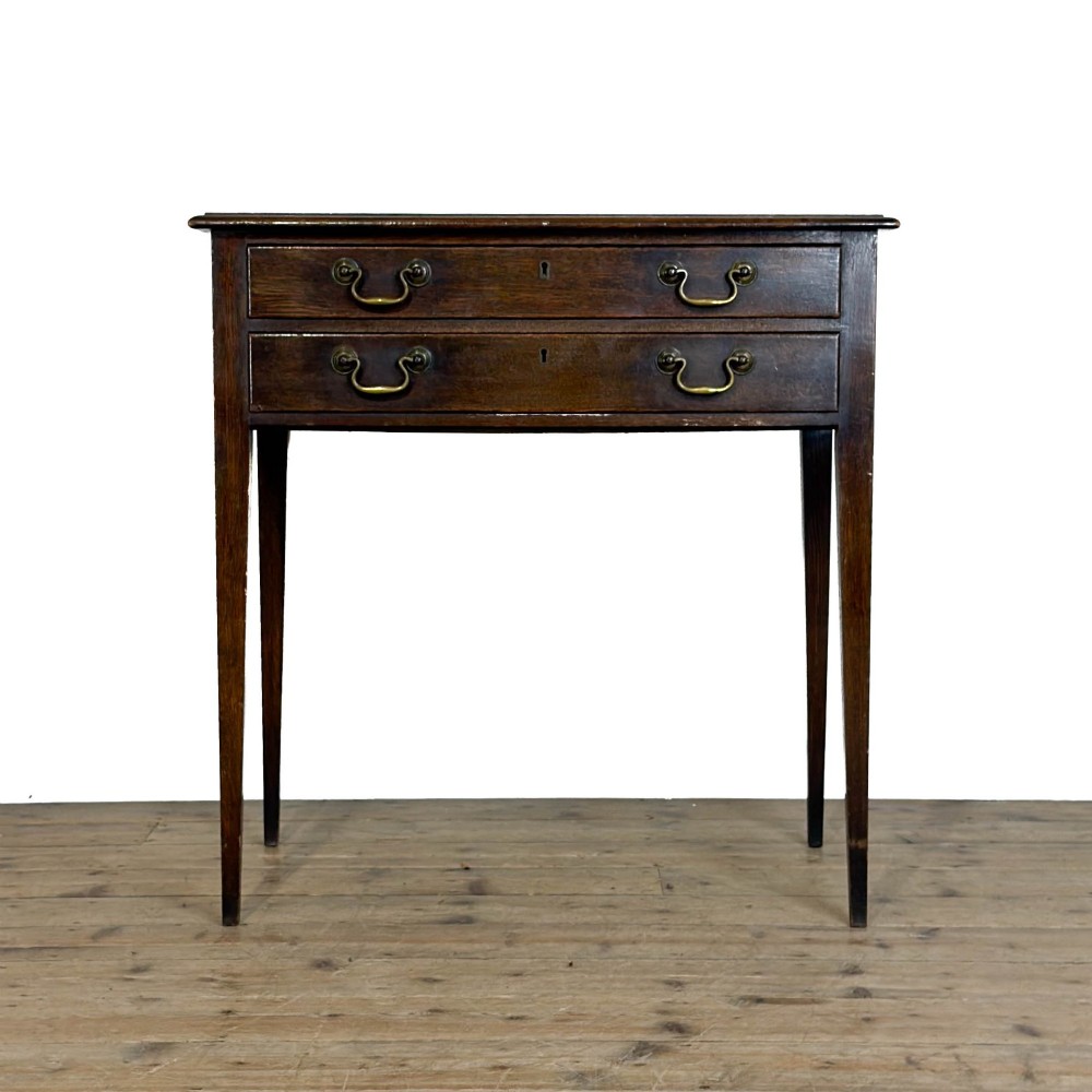 A dark oak lowboy table with two stacked drawers featuring brass drop handles and tapered square legs.