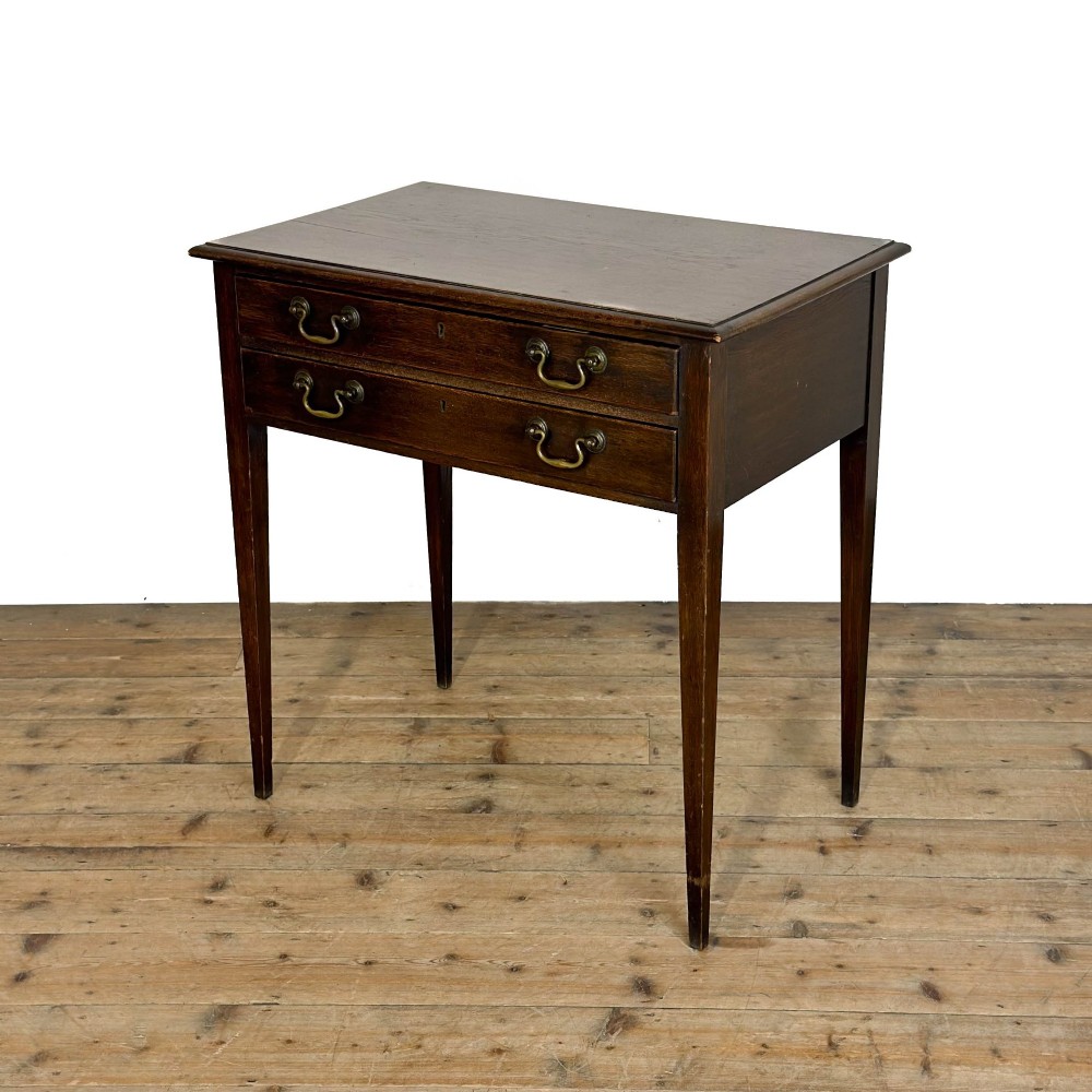 A dark oak lowboy table with two stacked drawers featuring brass drop handles and tapered square legs. View III