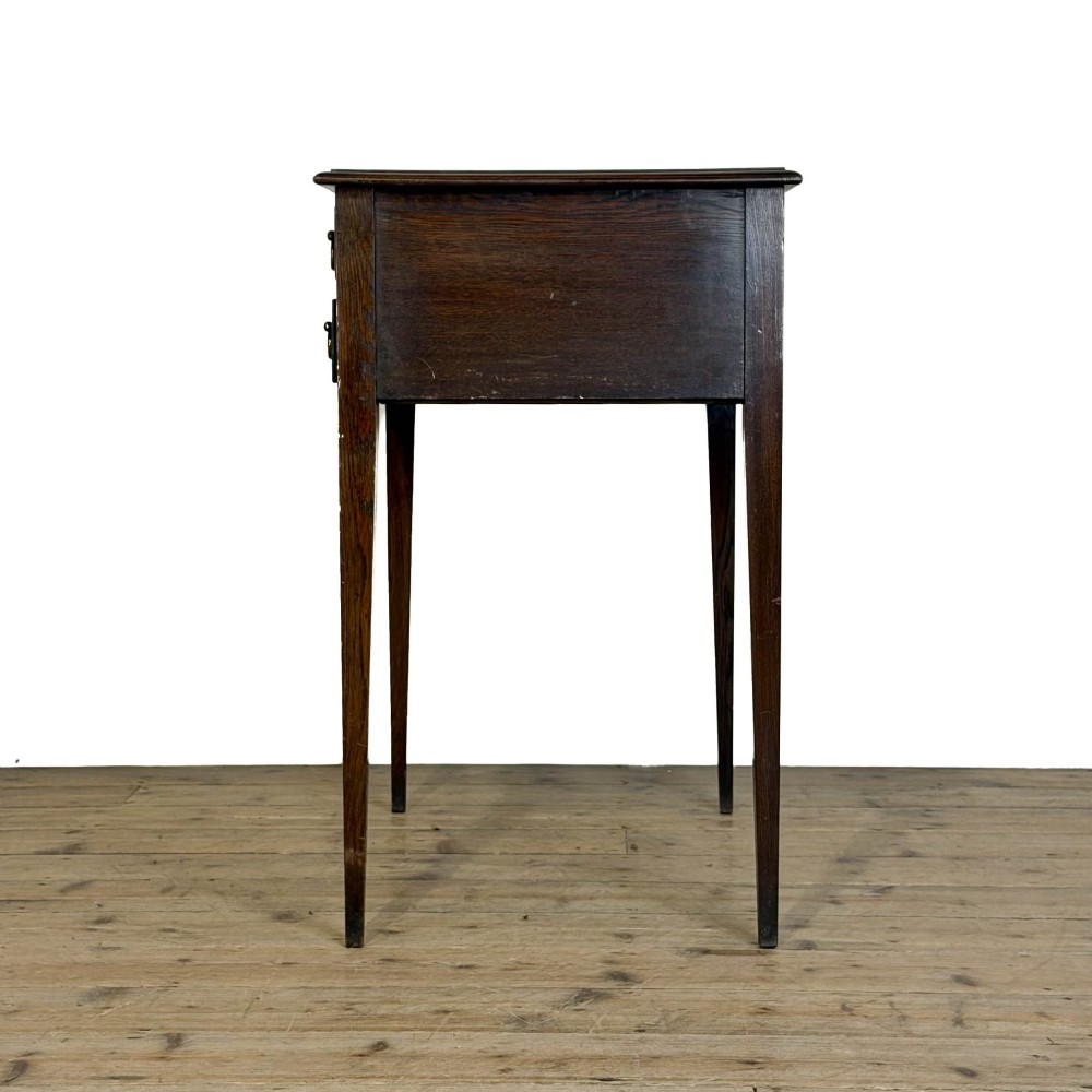 A dark oak lowboy table with two stacked drawers featuring brass drop handles and tapered square legs. View VI