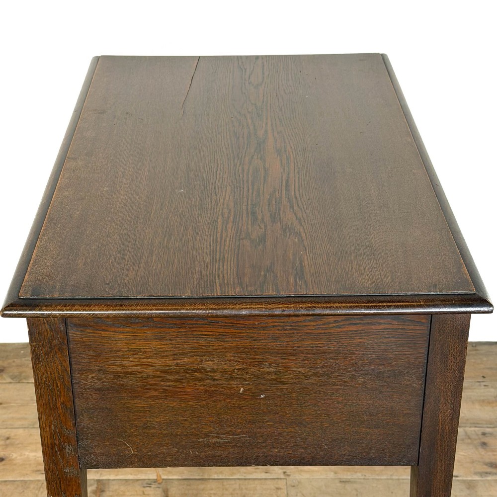 A dark oak lowboy table with two stacked drawers featuring brass drop handles and tapered square legs. View VII