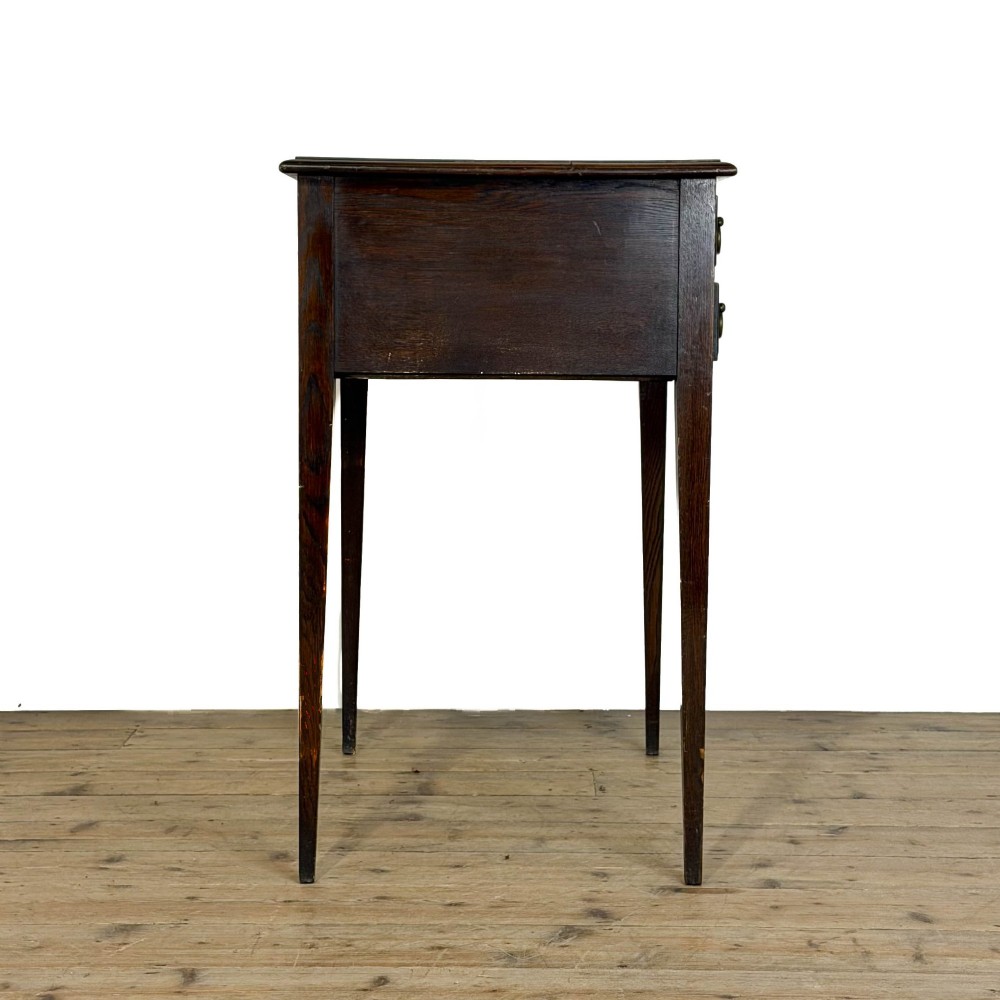 A dark oak lowboy table with two stacked drawers featuring brass drop handles and tapered square legs. View X