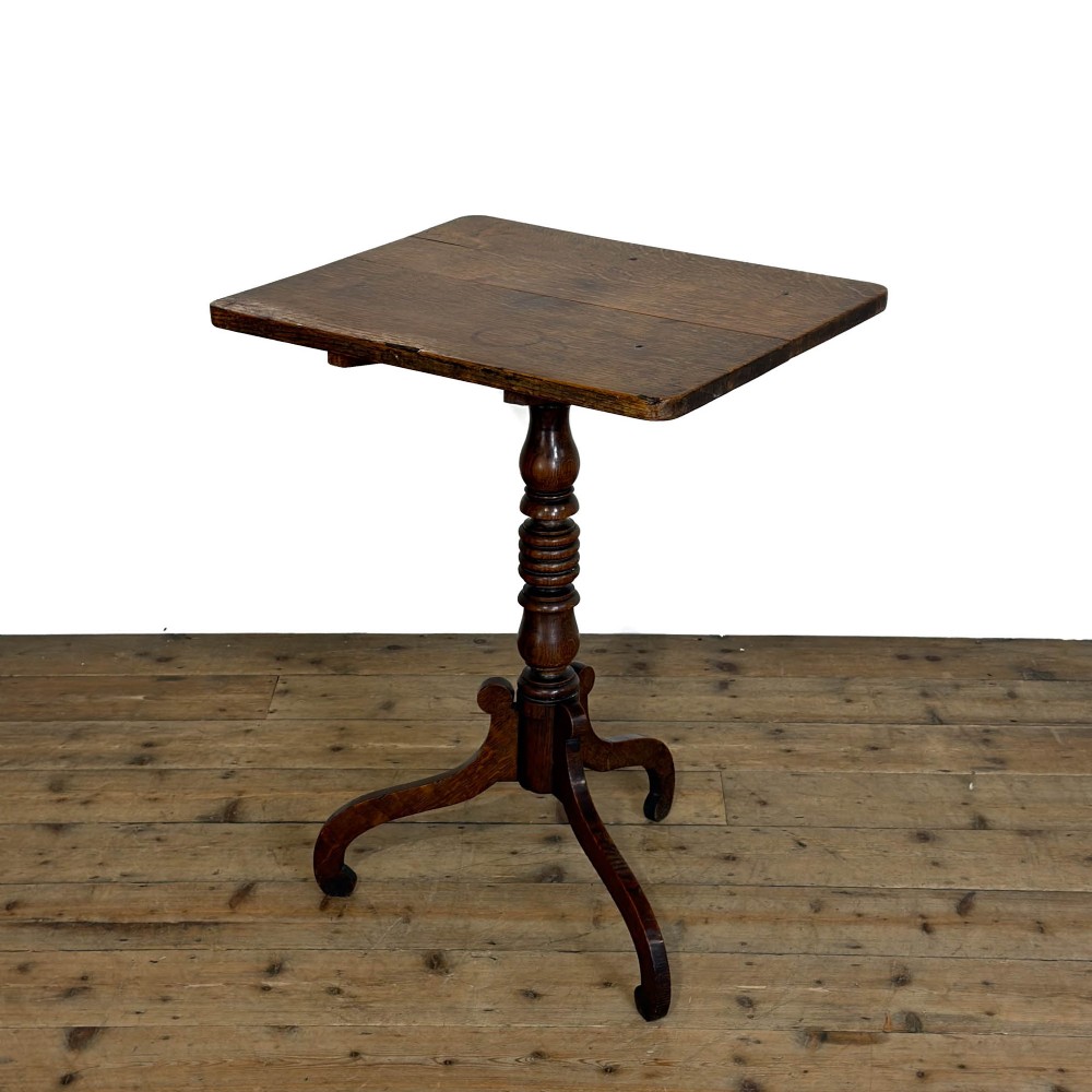 A 19th-century oak tilt-top table featuring a rectangular surface set upon a turned central column with three cabriole tripod legs.
