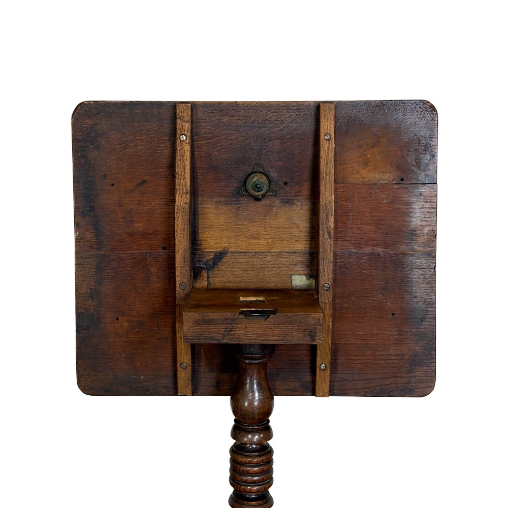 A 19th-century oak tilt-top table featuring a rectangular surface set upon a turned central column with three cabriole tripod legs. View VI