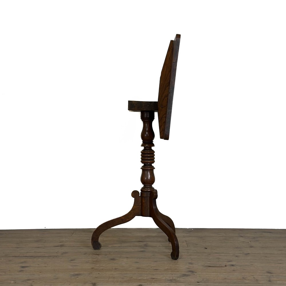 A 19th-century oak tilt-top table featuring a rectangular surface set upon a turned central column with three cabriole tripod legs. View VII