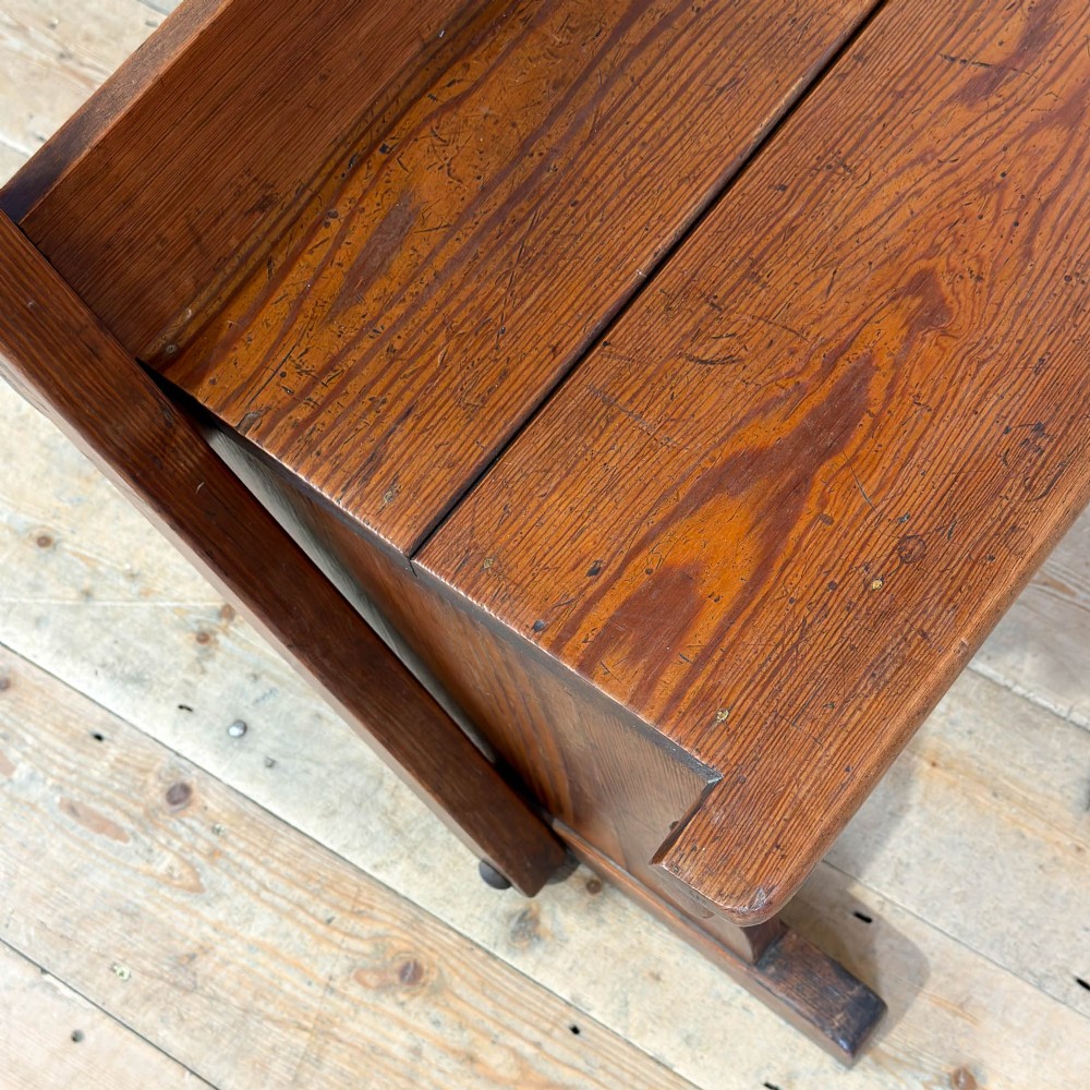 An antique pine bench featuring a pivoting backrest mechanism set above a long plank seat and shaped trestle end supports. View III