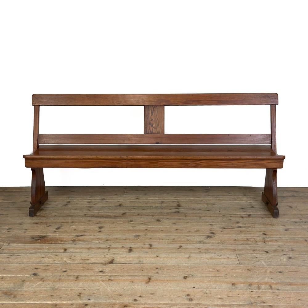 An antique pine bench featuring a pivoting backrest mechanism set above a long plank seat and shaped trestle end supports. View IV