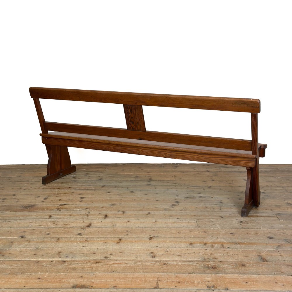 An antique pine bench featuring a pivoting backrest mechanism set above a long plank seat and shaped trestle end supports. View VII
