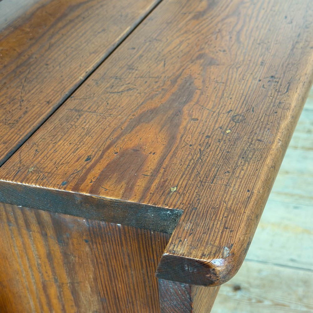 An antique pine bench featuring a pivoting backrest mechanism set above a long plank seat and shaped trestle end supports. View XI