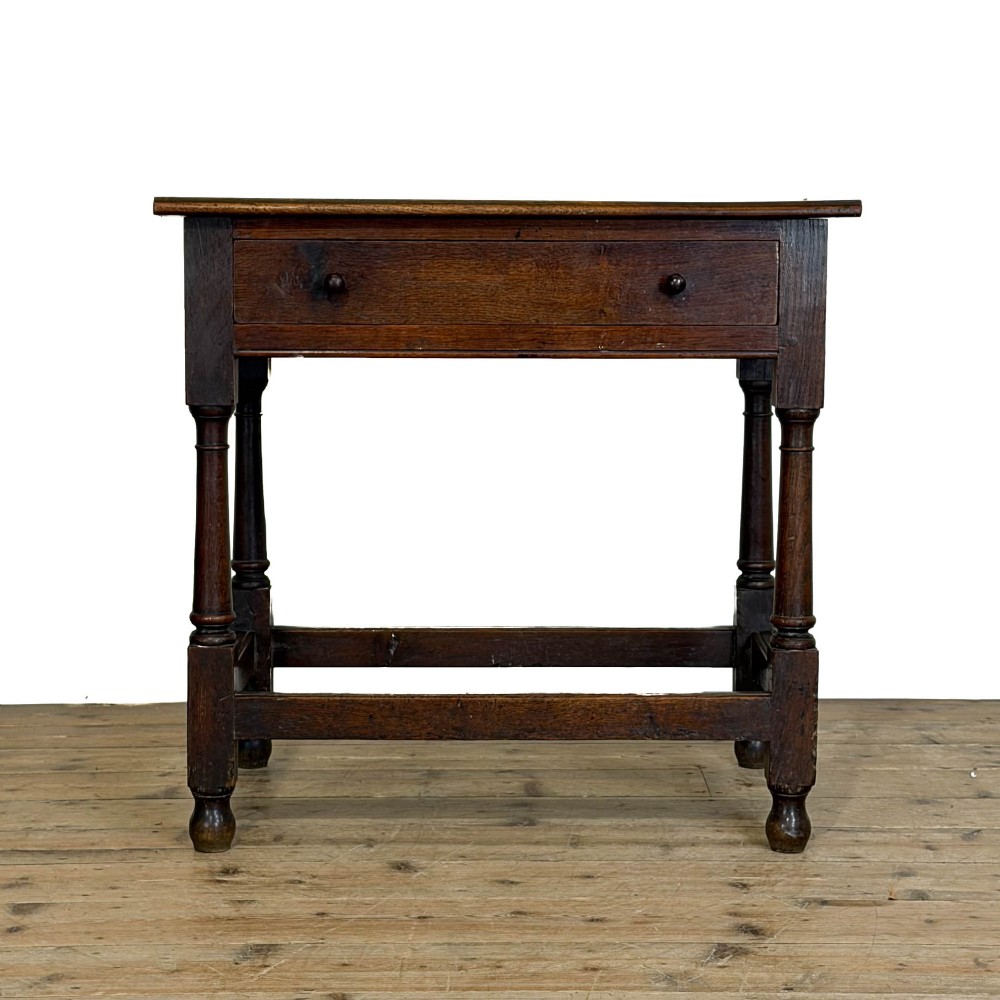 An 18th-century dark oak side table featuring a single drawer with turned wooden knobs, turned front legs, and lower stretchers.