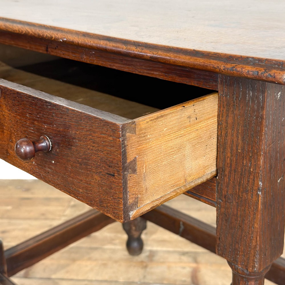 An 18th-century dark oak side table featuring a single drawer with turned wooden knobs, turned front legs, and lower stretchers. View V