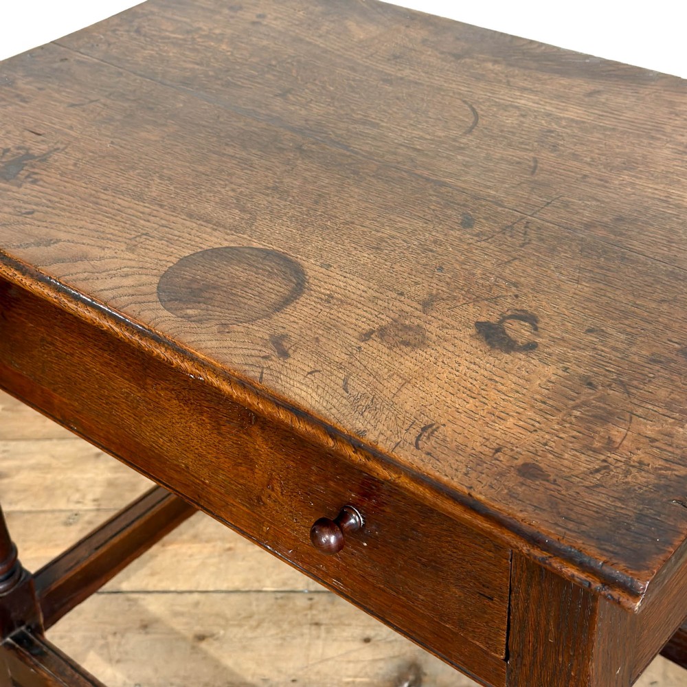 An 18th-century dark oak side table featuring a single drawer with turned wooden knobs, turned front legs, and lower stretchers. View VI