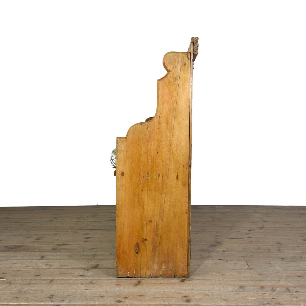 An antique pine church pew bench featuring a high vertical plank back, shaped scrolled side arms, a lower foot rail, and a patterned green fabric seat cushion. View VI