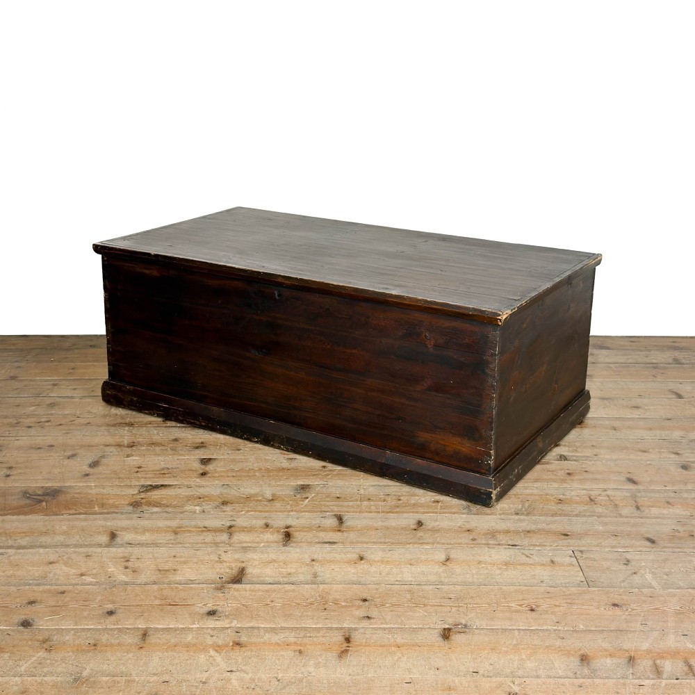 An antique stained pine blanket box featuring a flat hinged lid, dark wood finish, moulded plinth base, and central keyhole escutcheon. View III