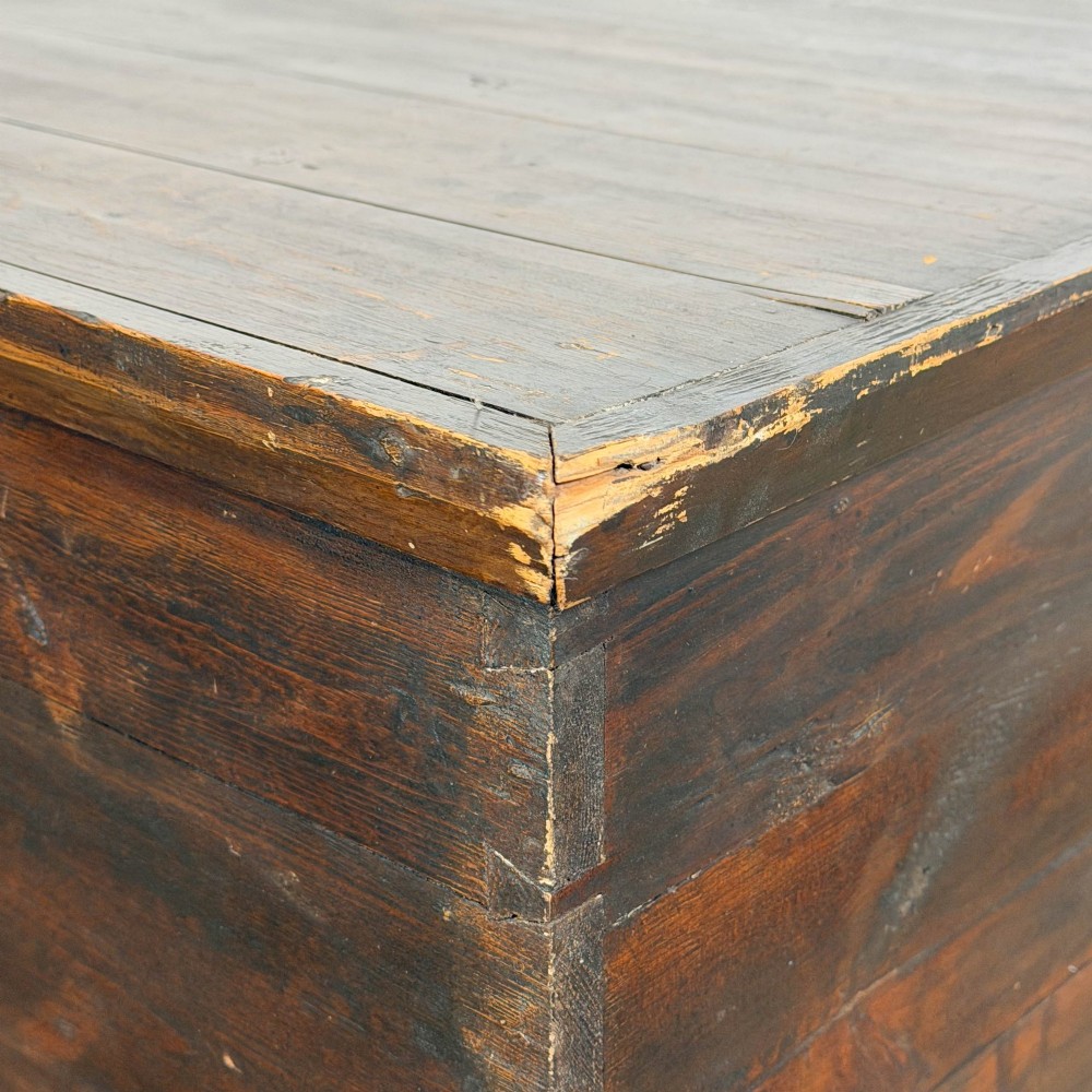 An antique stained pine blanket box featuring a flat hinged lid, dark wood finish, moulded plinth base, and central keyhole escutcheon. View V