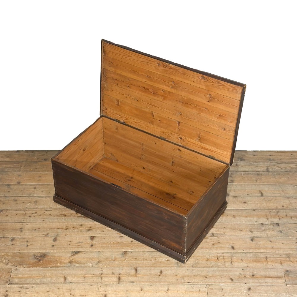 An antique stained pine blanket box featuring a flat hinged lid, dark wood finish, moulded plinth base, and central keyhole escutcheon. View VI