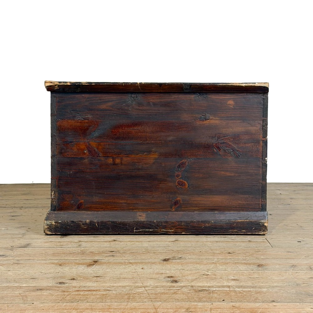 An antique stained pine blanket box featuring a flat hinged lid, dark wood finish, moulded plinth base, and central keyhole escutcheon. View VIII