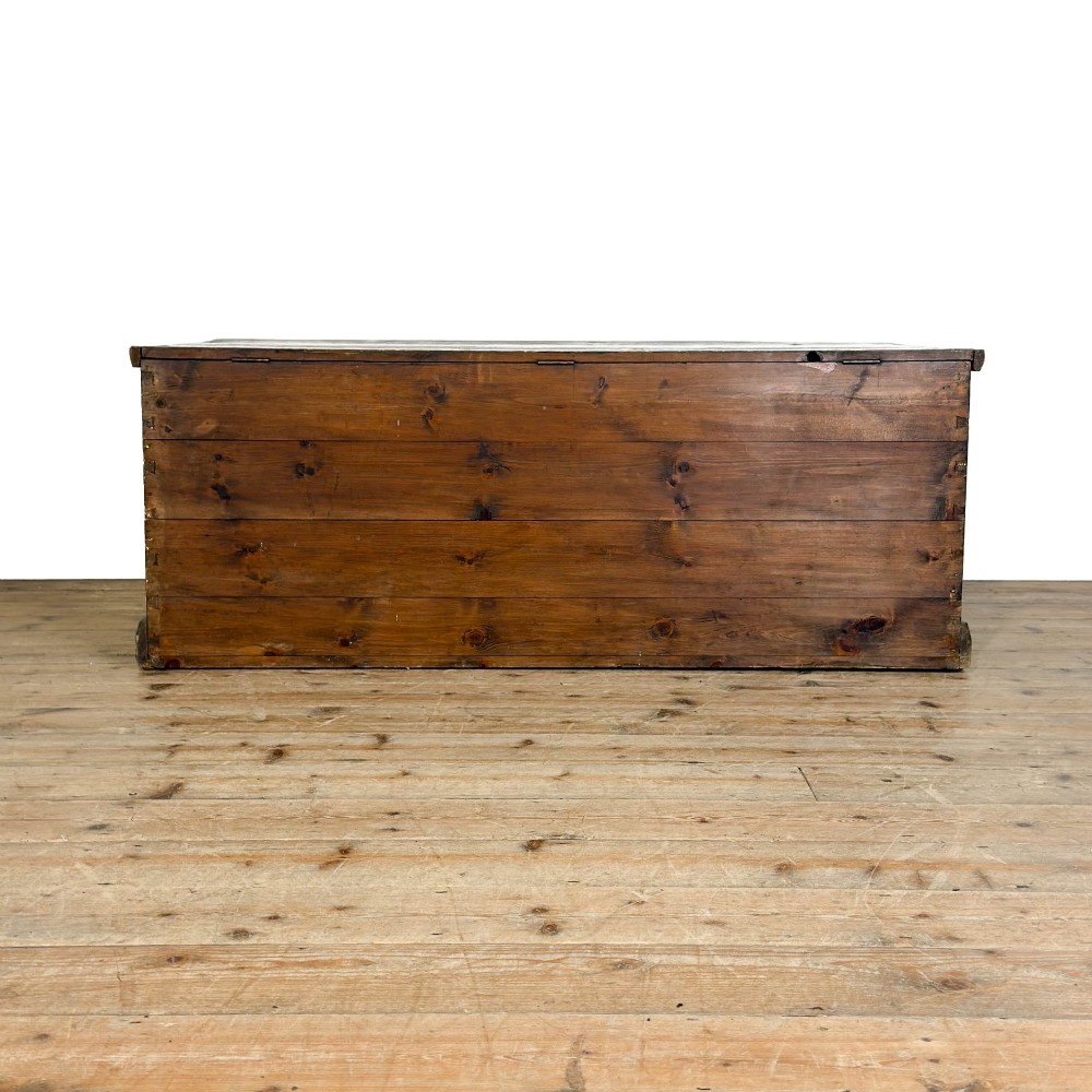 An antique stained pine blanket box featuring a flat hinged lid, dark wood finish, moulded plinth base, and central keyhole escutcheon. View IX