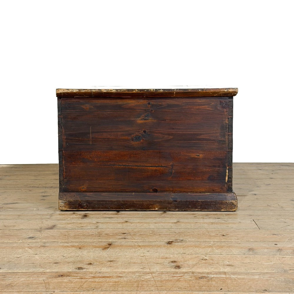 An antique stained pine blanket box featuring a flat hinged lid, dark wood finish, moulded plinth base, and central keyhole escutcheon. View X