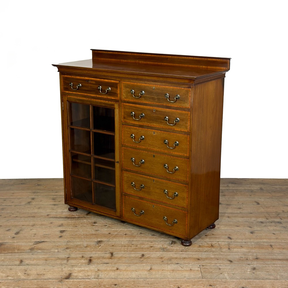An Edwardian mahogany cabinet featuring an eight-pane glazed door on the left beside a vertical bank of six drawers with brass handles. View V