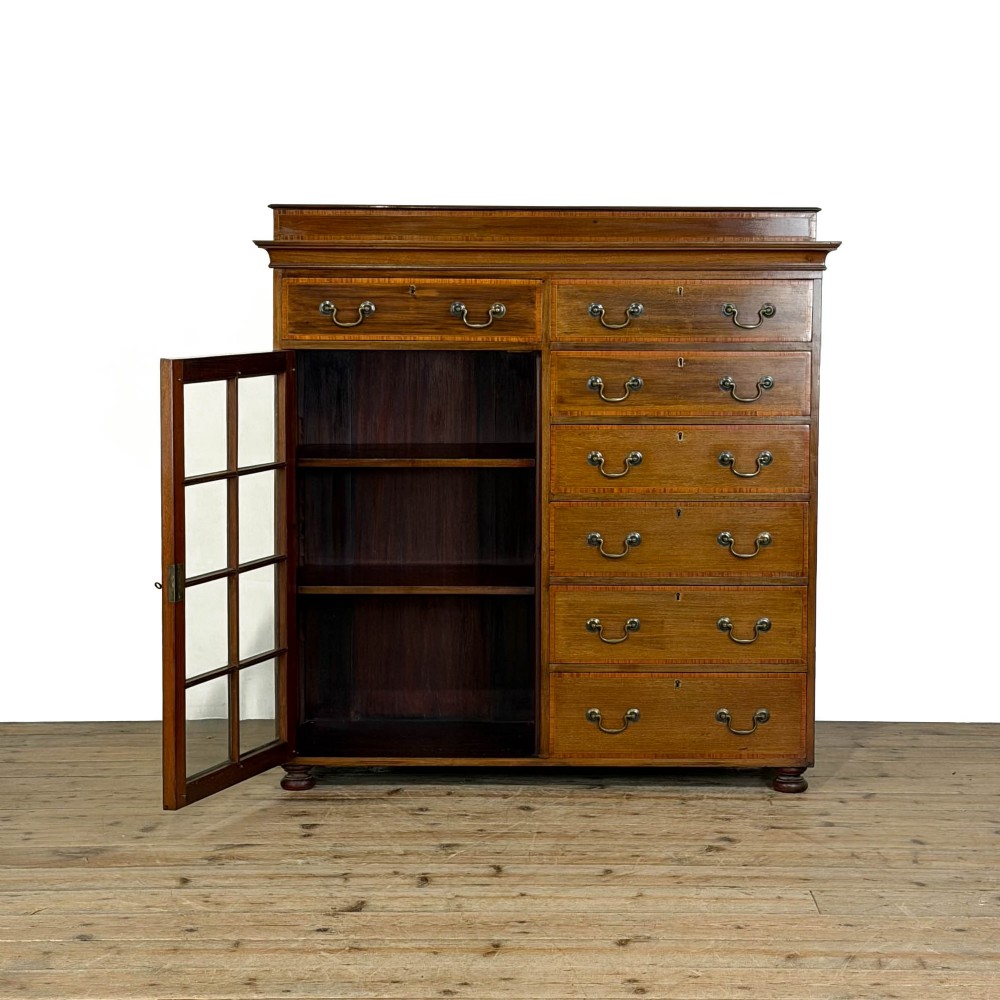 An Edwardian mahogany cabinet featuring an eight-pane glazed door on the left beside a vertical bank of six drawers with brass handles. View IX