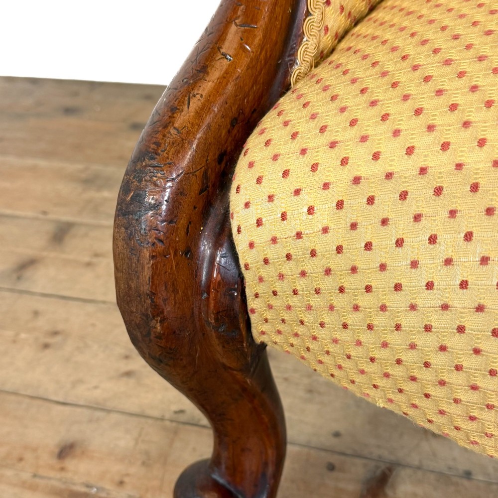 A Victorian upholstered armchair featuring a button-backed yellow patterned fabric seat and a carved mahogany frame with brass castors. View II