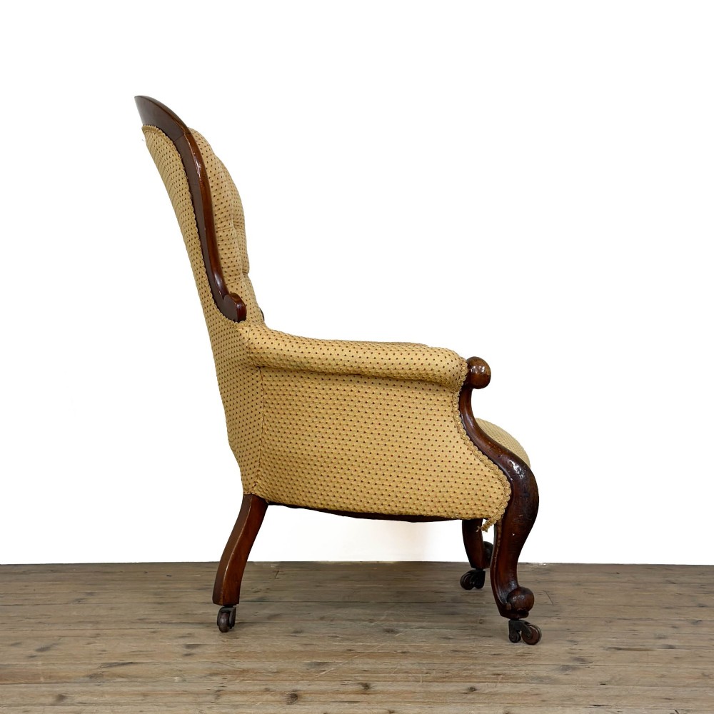 A Victorian upholstered armchair featuring a button-backed yellow patterned fabric seat and a carved mahogany frame with brass castors. View VIII