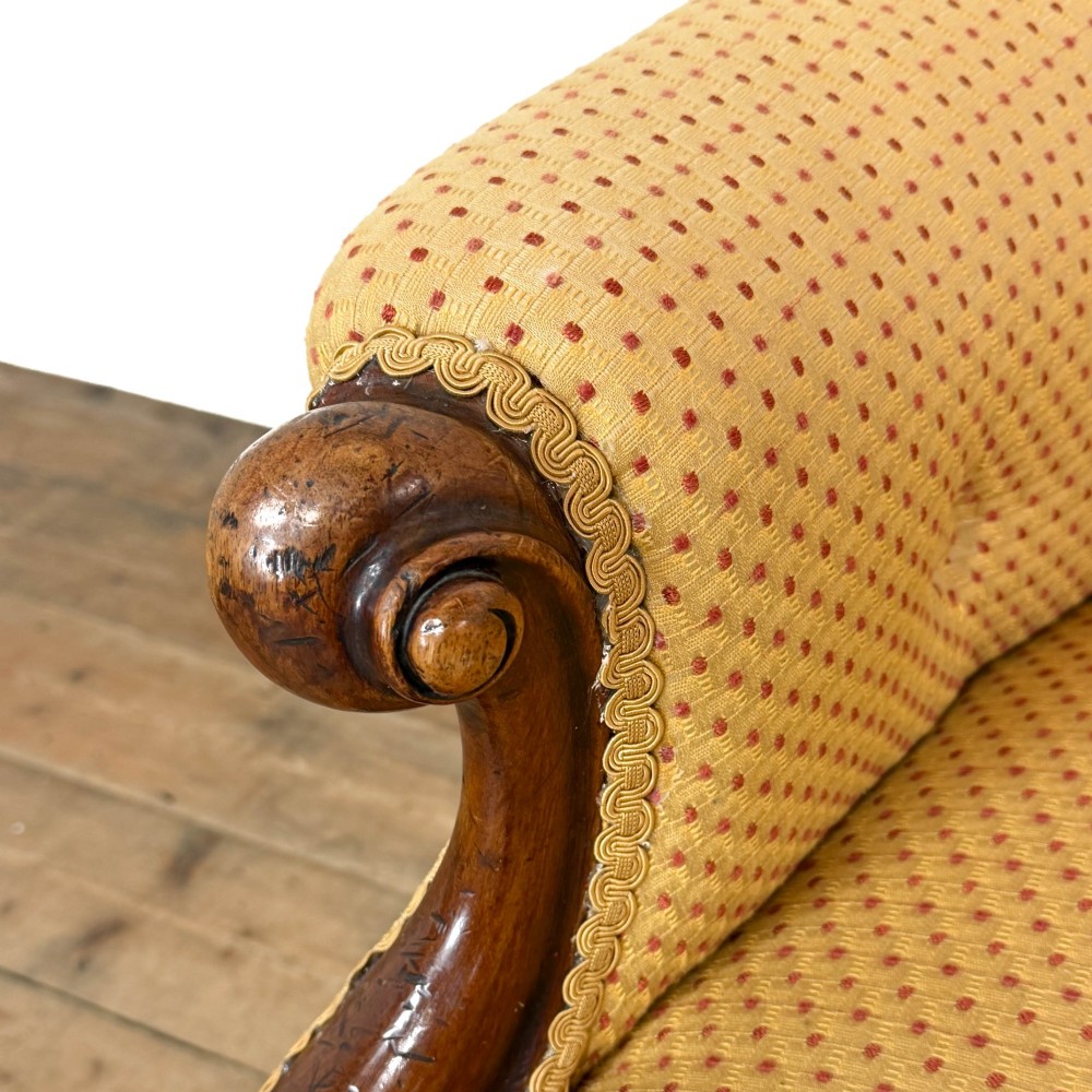 A Victorian upholstered armchair featuring a button-backed yellow patterned fabric seat and a carved mahogany frame with brass castors. View X