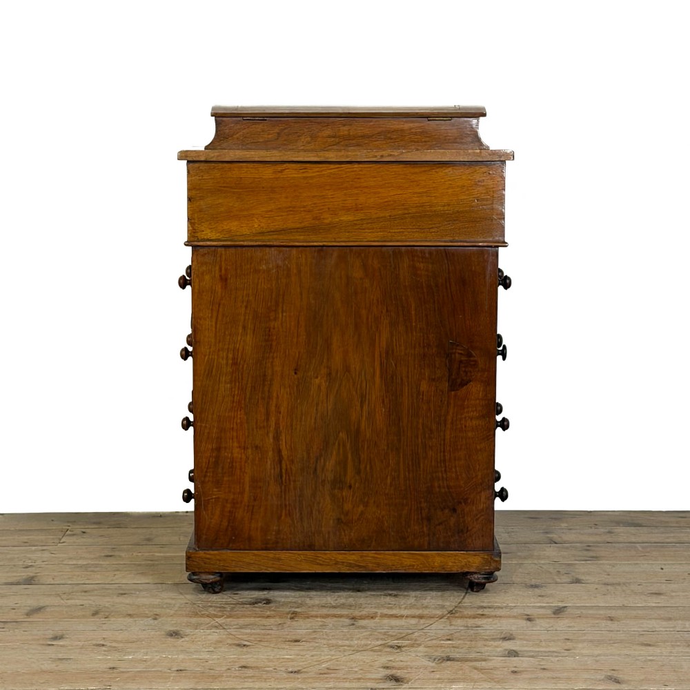 An antique Victorian walnut Davenport desk featuring a slanted leather-lined writing surface, an upper stationery compartment, and four drawers on the side. View IV