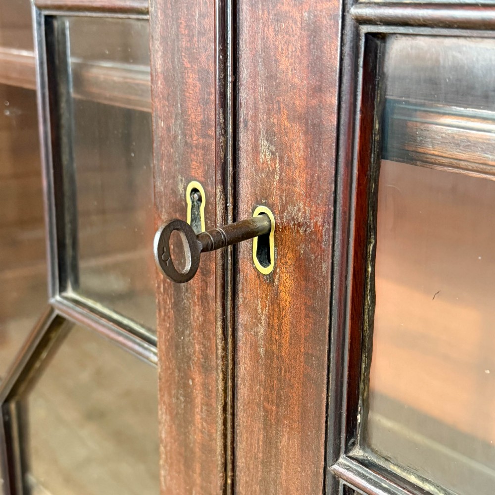 A 19th-century dark mahogany low bookcase featuring two glazed doors with geometric astragal glazing bars, dentil moulding at the top cornice, and bracket feet. View IV