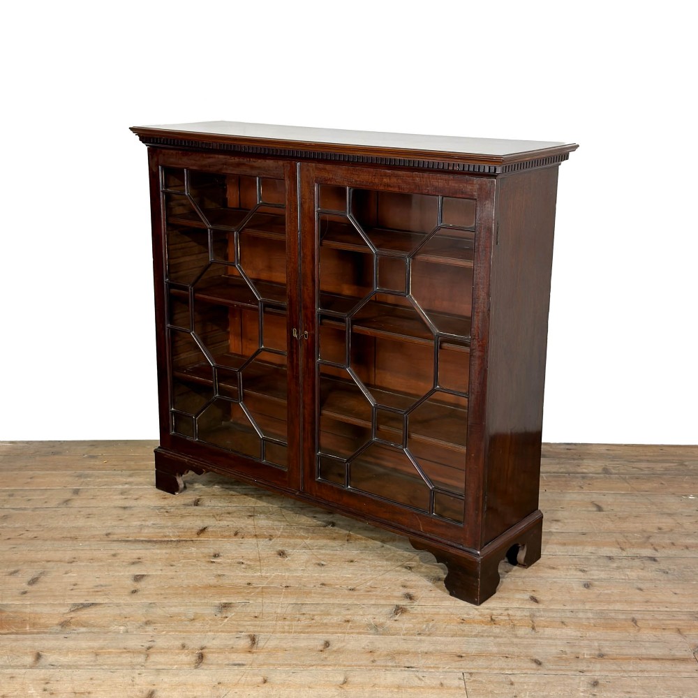 A 19th-century dark mahogany low bookcase featuring two glazed doors with geometric astragal glazing bars, dentil moulding at the top cornice, and bracket feet. View V
