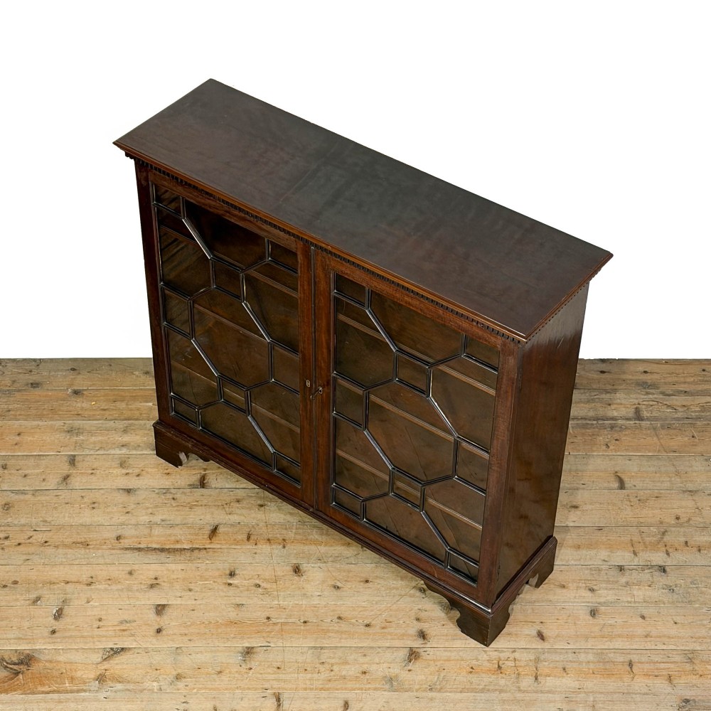 A 19th-century dark mahogany low bookcase featuring two glazed doors with geometric astragal glazing bars, dentil moulding at the top cornice, and bracket feet. View VI