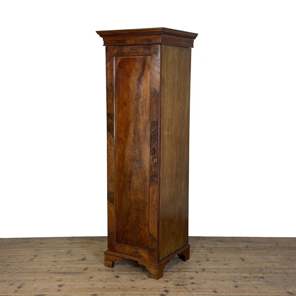 A tall single door mahogany wardrobe featuring a moulded cornice, flame mahogany veneer door panel, and bracket feet.