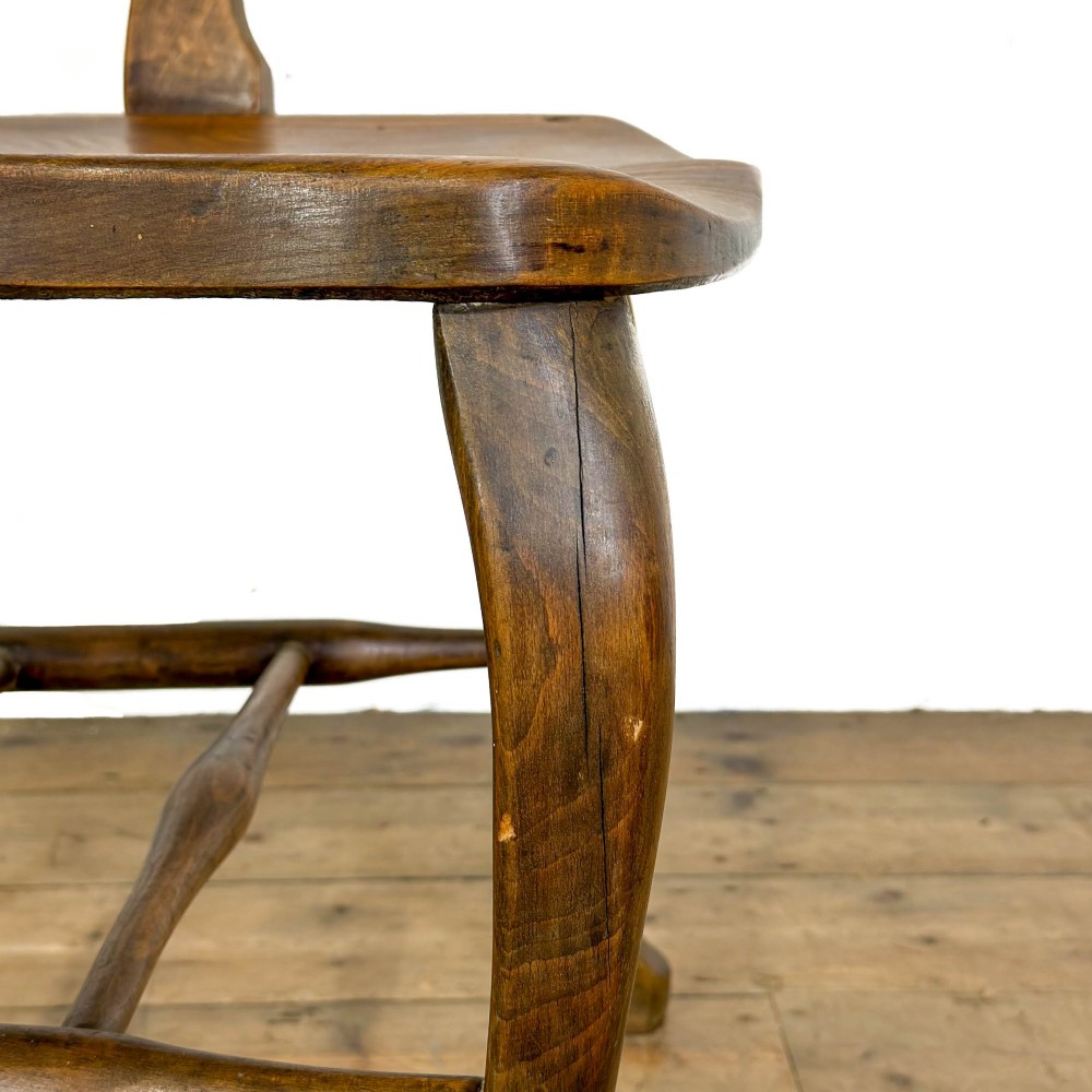 An antique warm brown oak office armchair with a slatted backrest, curved armrests, a contoured wooden seat, and turned legs. View IV