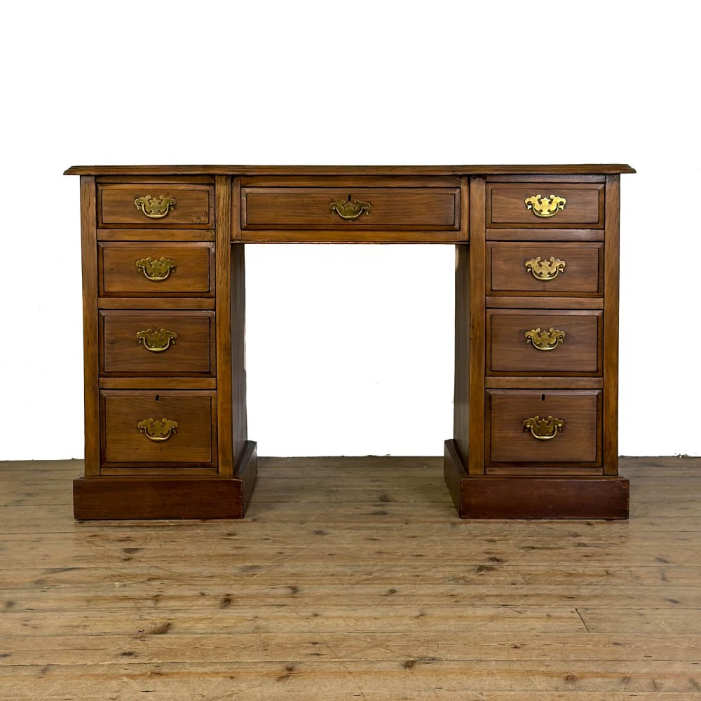 An Edwardian timber kneehole desk featuring a central drawer flanked by twin pedestals with brass handles and a rectangular top.