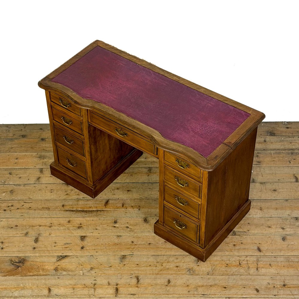 An Edwardian timber kneehole desk featuring a central drawer flanked by twin pedestals with brass handles and a rectangular top. View III