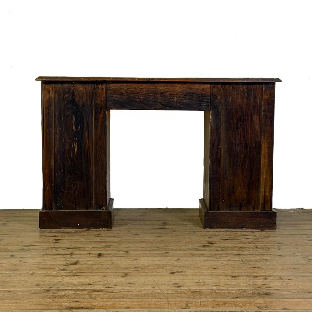 An Edwardian timber kneehole desk featuring a central drawer flanked by twin pedestals with brass handles and a rectangular top. View VI