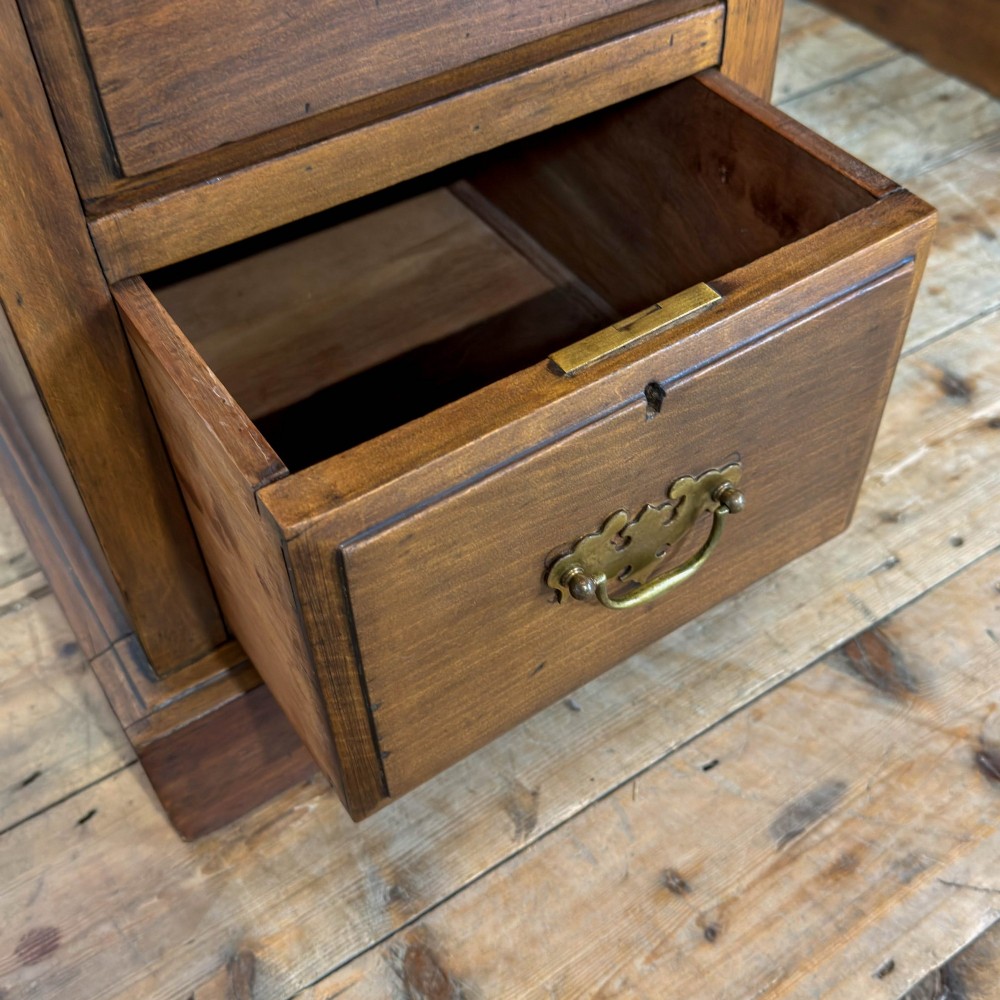 An Edwardian timber kneehole desk featuring a central drawer flanked by twin pedestals with brass handles and a rectangular top. View VIII