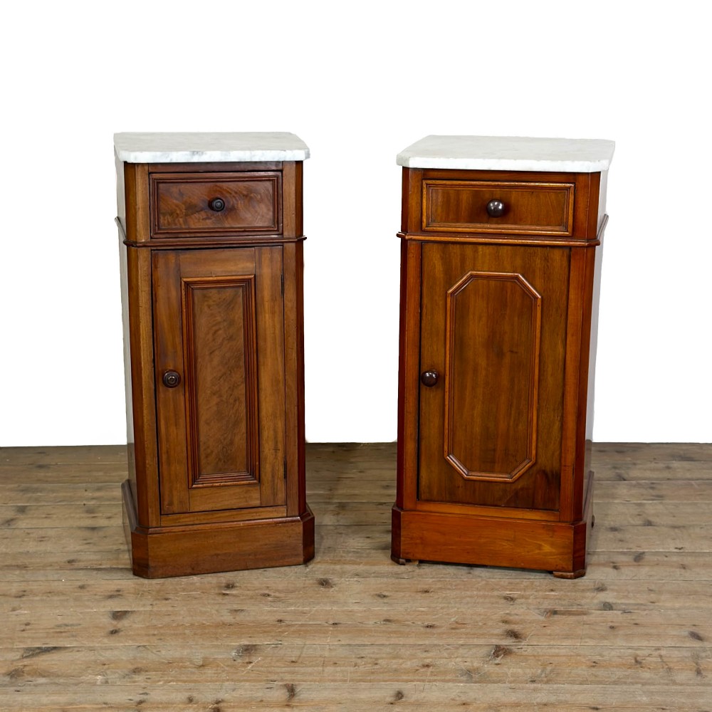 A matching pair of French Louis Philippe style walnut bedside cabinets with white marble tops, upper drawers, lower cupboard doors, and plinth bases.