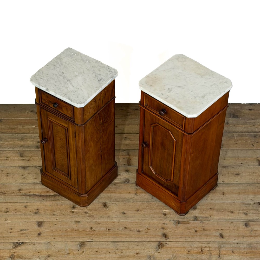 A matching pair of French Louis Philippe style walnut bedside cabinets with white marble tops, upper drawers, lower cupboard doors, and plinth bases. View V