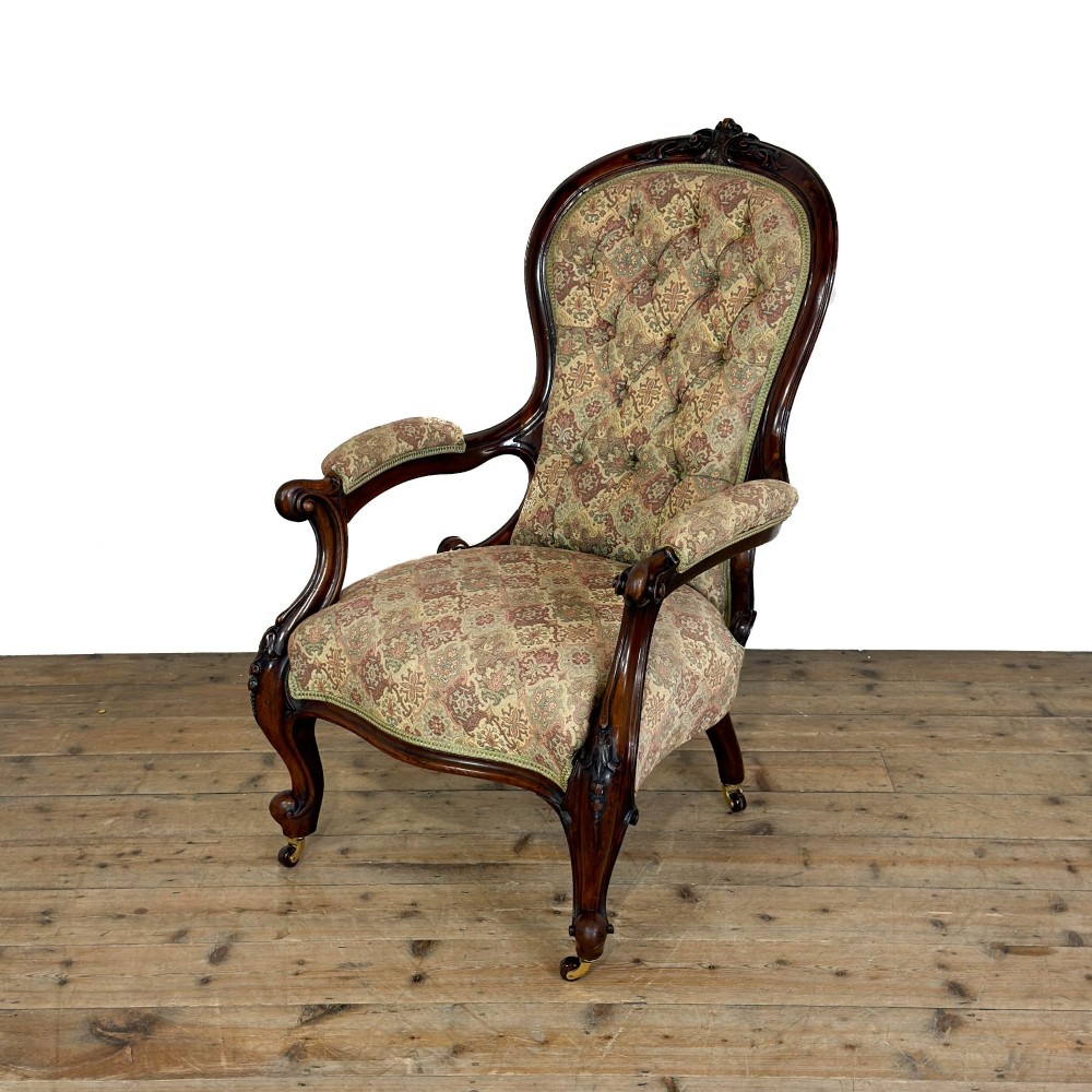 Victorian carved mahogany armchair with deep button-backed floral tapestry upholstery, curved armrests, and cabriole legs on brass castors. View II