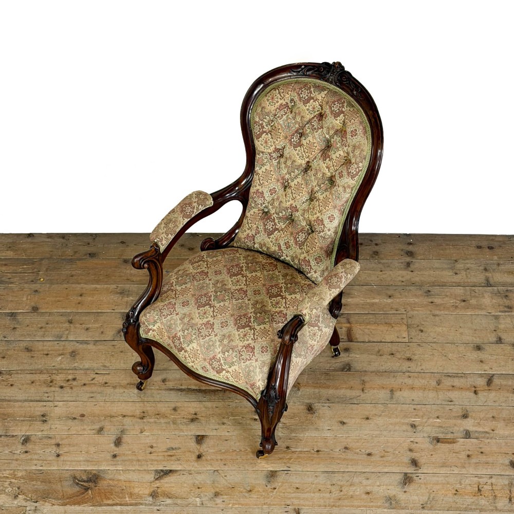 Victorian carved mahogany armchair with deep button-backed floral tapestry upholstery, curved armrests, and cabriole legs on brass castors. View III