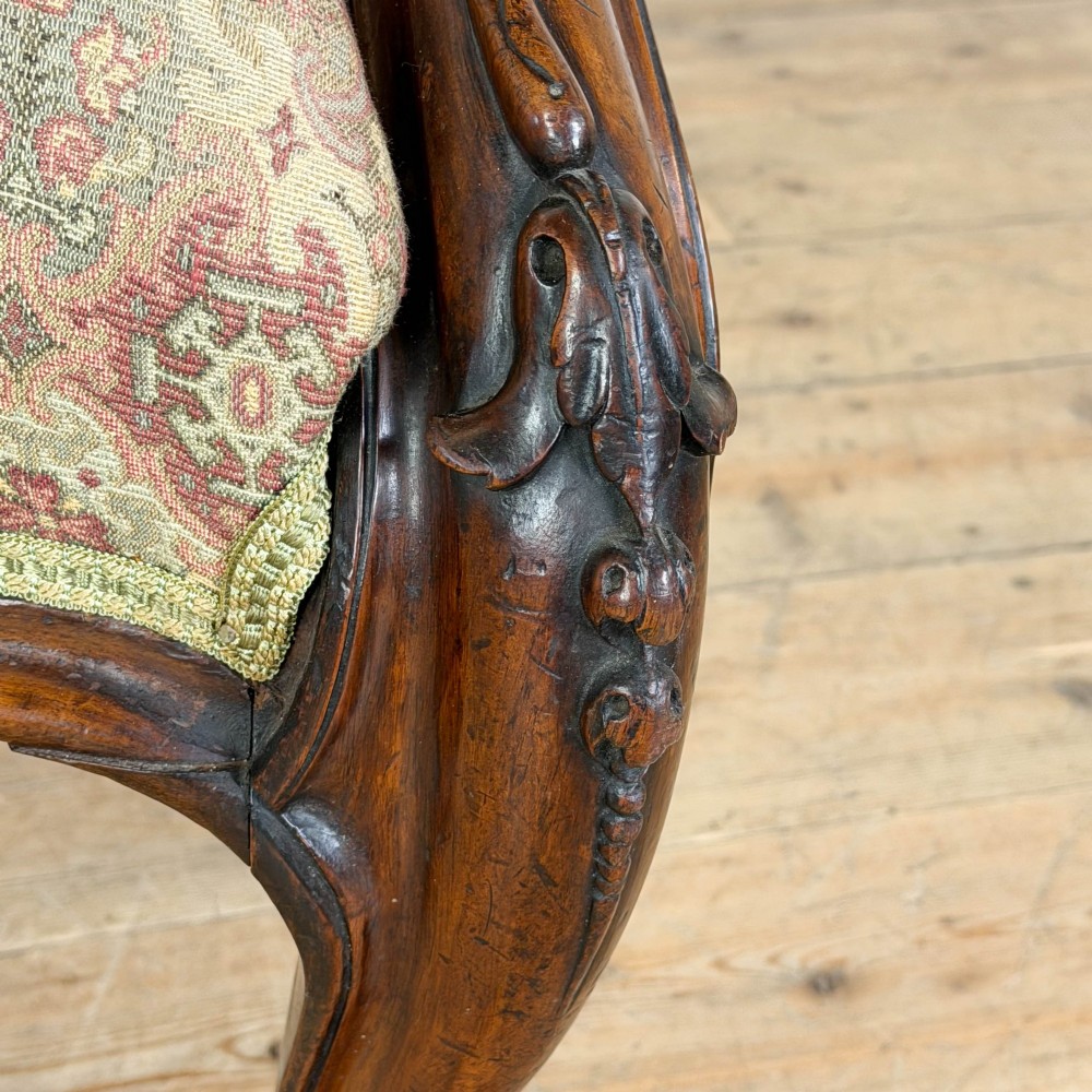 Victorian carved mahogany armchair with deep button-backed floral tapestry upholstery, curved armrests, and cabriole legs on brass castors. View VIII