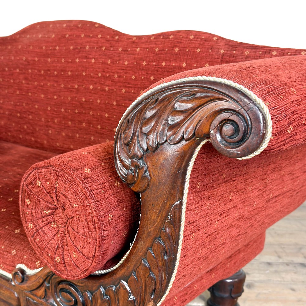 An antique Victorian walnut sofa with carved scroll arms, red patterned fabric upholstery, bolster cushions, and turned legs. View IV