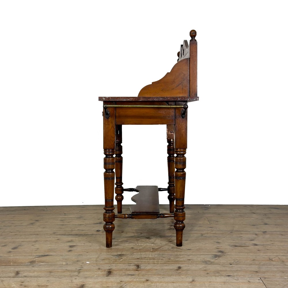 An Edwardian wooden washstand with a carved splashback housing floral glazed tiles, a single drawer with drop handles, turned legs, and an undertier shelf. View VII