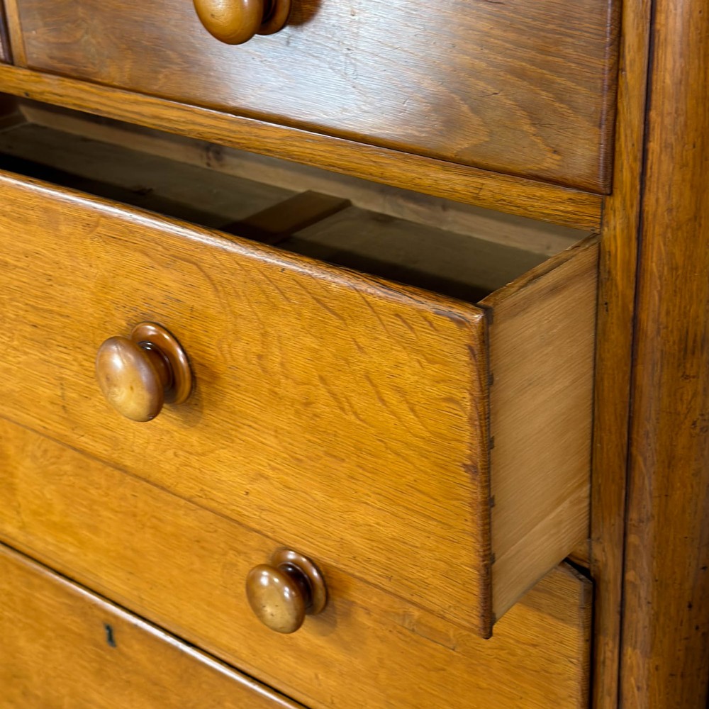 A Victorian light oak chest of drawers featuring a two-over-three drawer configuration with turned wooden knobs and turned feet. View II
