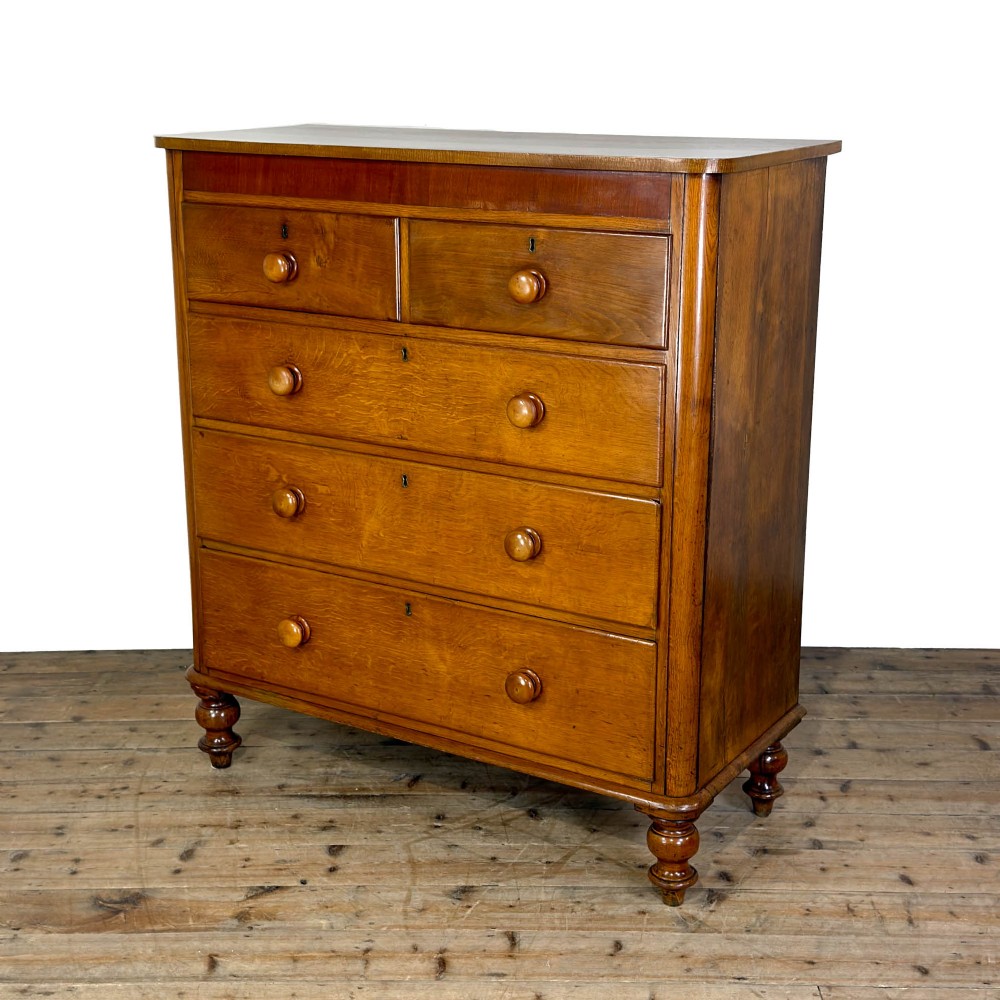 A Victorian light oak chest of drawers featuring a two-over-three drawer configuration with turned wooden knobs and turned feet. View IV